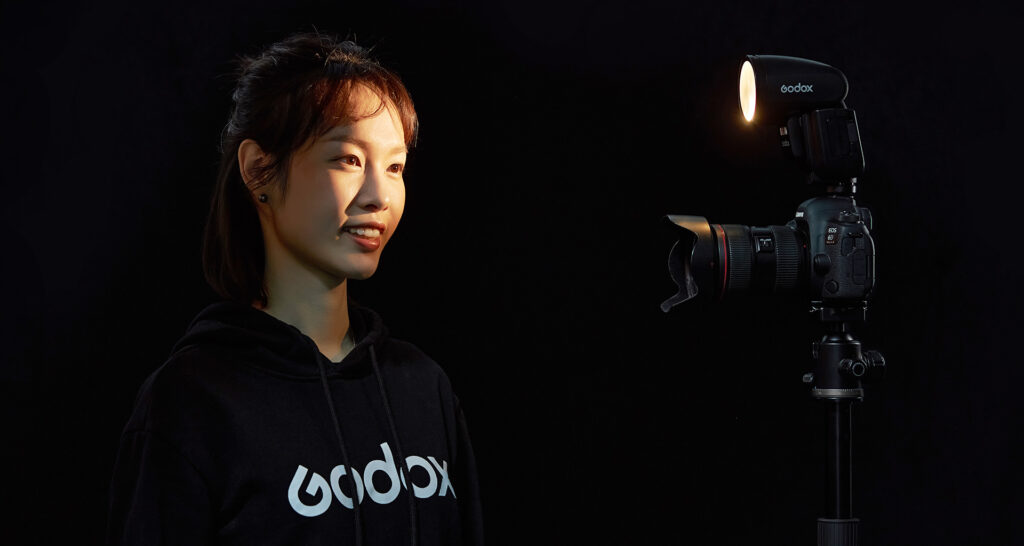 Godox V1 Pro välklambi ees seisab tumetäine ja tumedate silmadega hiinlanna