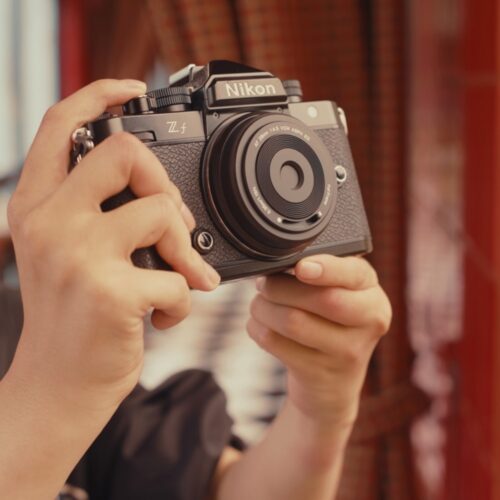 Inimene hoiab käes Nikon Zf kaamerat, mille ette on kinnitatud Viltrox AF 28mm f/4.5