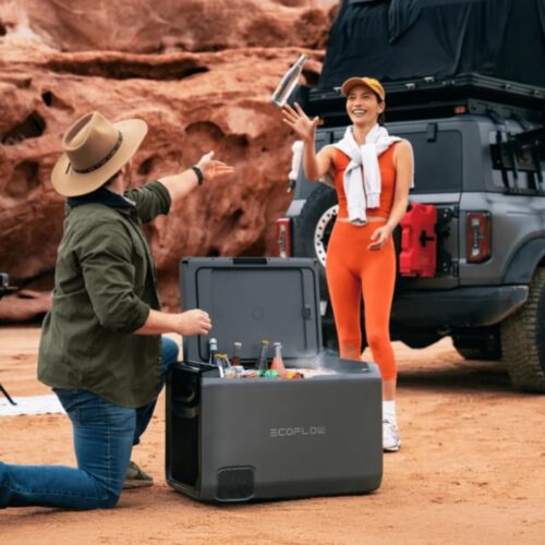 Kaasaskantav külmik EcoFlow Glacier Classic on auto taga maas ja mees haarab sellest joogipudeli ning viskab naisele