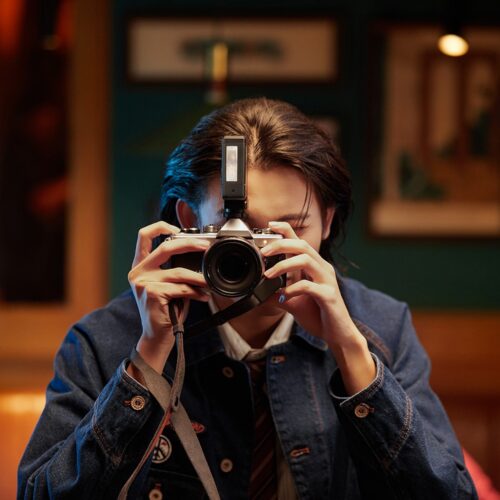 Fotograaf pildistab retrokaameraga, mille peal on Godox Lux Junior II